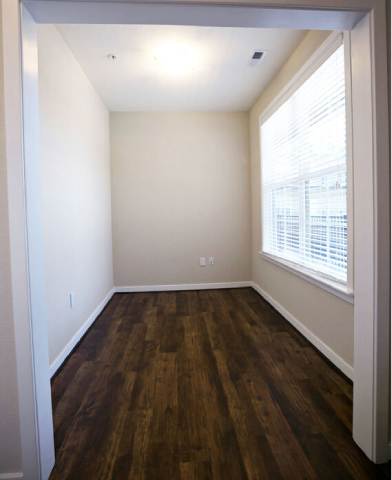 A room with wooden floors and a window with blinds.