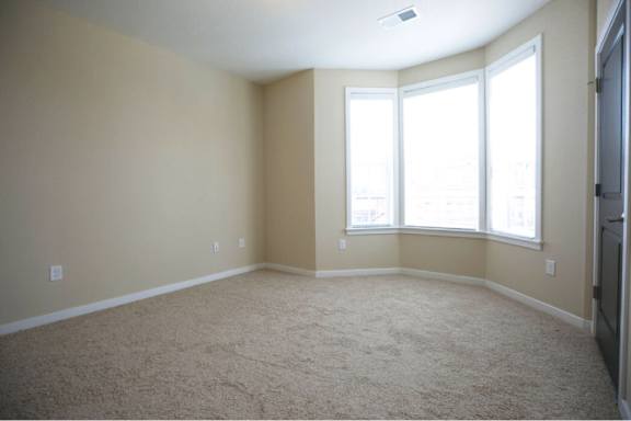A room with a carpeted floor and a window.