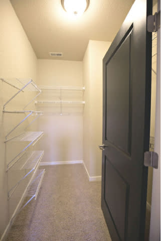 A walk-in closet with a black door and white shelves.