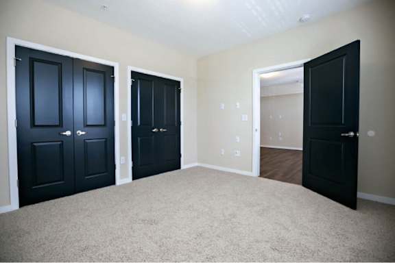 Three black doors are in a room with carpeting.