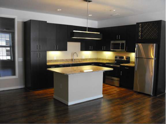 A modern kitchen with black cabinets and stainless steel appliances.
