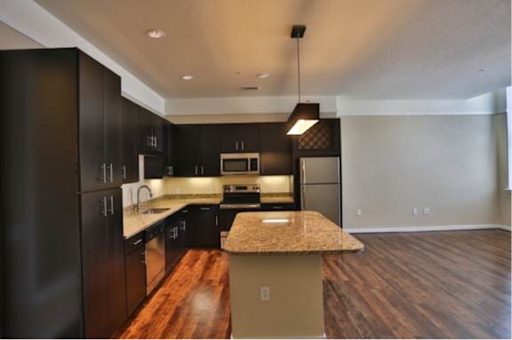 A modern kitchen with dark wood cabinets and a granite countertop.