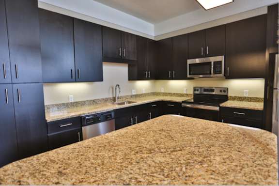 A kitchen with dark cabinets and granite countertops.