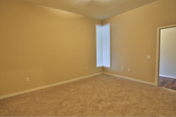 A room with a carpeted floor and a doorway leading to another room.