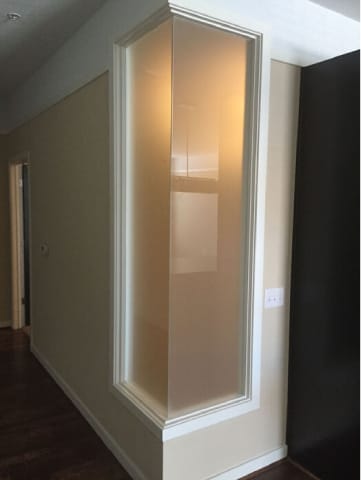 A glass door in a room with a black wall on the right.