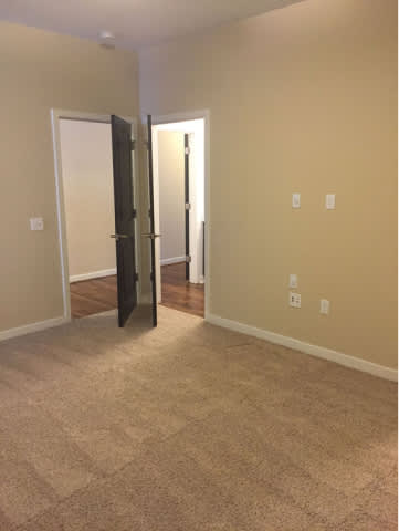 A hallway with a carpeted floor and a white door.