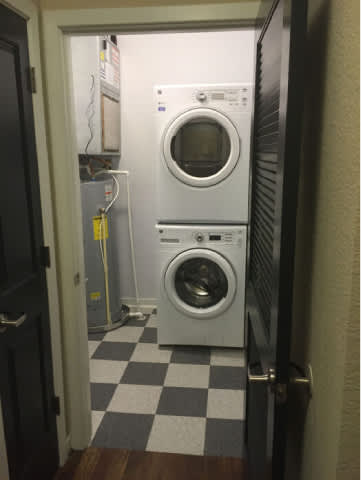 A white dryer is in a small room with a checkered floor.