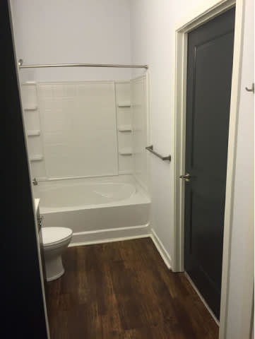 A white bathroom with a toilet, tub, and door.