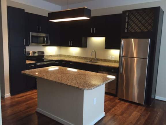 A kitchen with a granite countertop and stainless steel appliances.