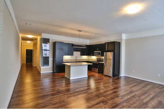 A spacious kitchen with dark wood floors and modern appliances.