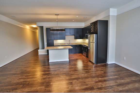 A kitchen with dark wood floors and a black refrigerator.
