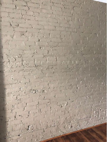A white brick wall with a wooden floor.