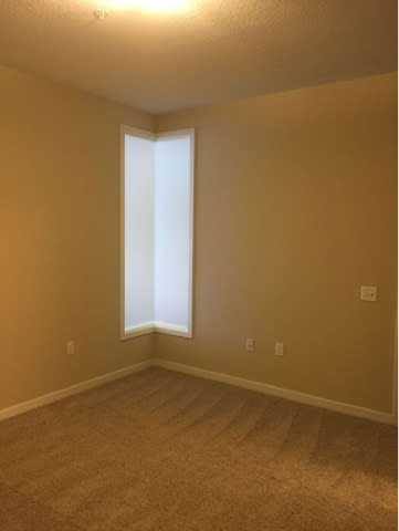 A room with a carpeted floor and a window.