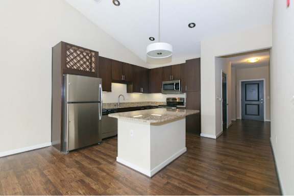A kitchen with a refrigerator, microwave, and oven.