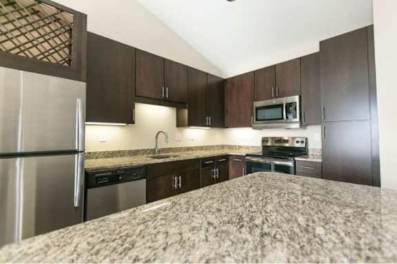 A kitchen with a refrigerator, microwave, oven, and sink.