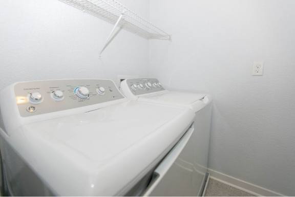 A white washing machine with a shelf above it.