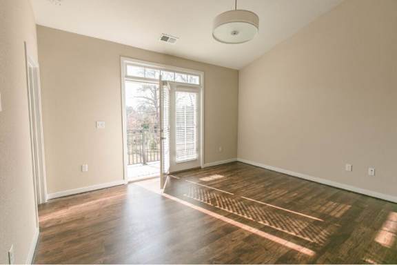 A room with wooden floors and a sliding glass door leading outside.