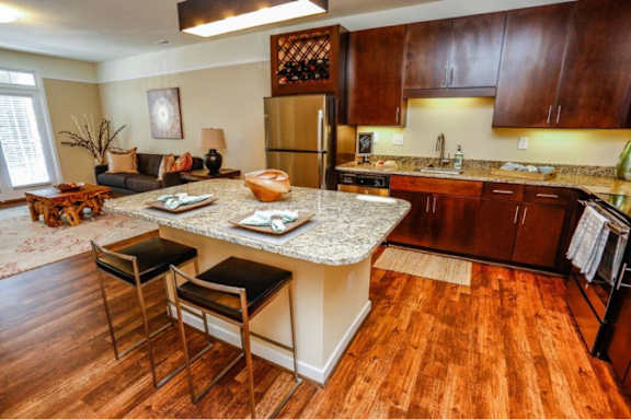 A kitchen with a granite countertop and wooden floors.