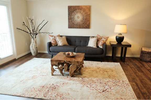 A living room with a black couch, a wooden coffee table, and a large painting on the wall.