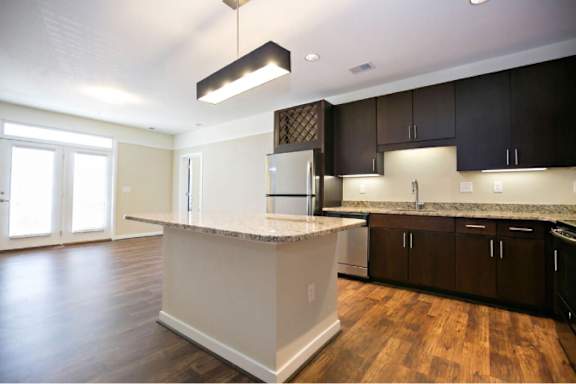 A kitchen with dark brown cabinets and a white island.