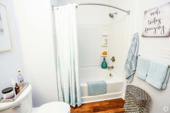 A bathroom with a white shower curtain and a white toilet.