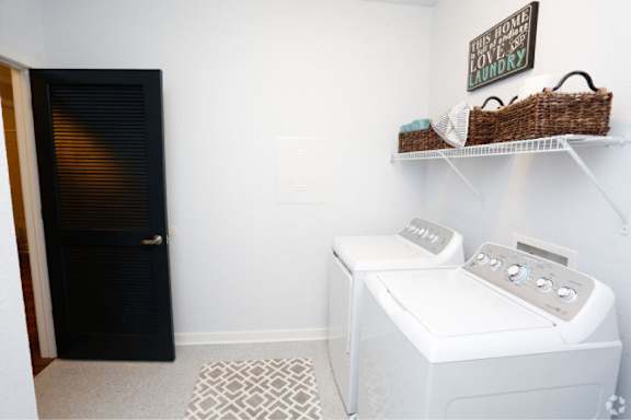 A laundry room with a washer and dryer and a sign on the wall.