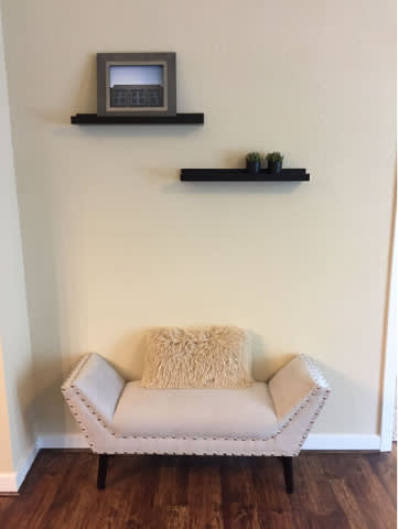 A white couch with a pillow and a picture frame on the wall.