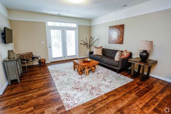 A living room with a brown rug and wooden floors.