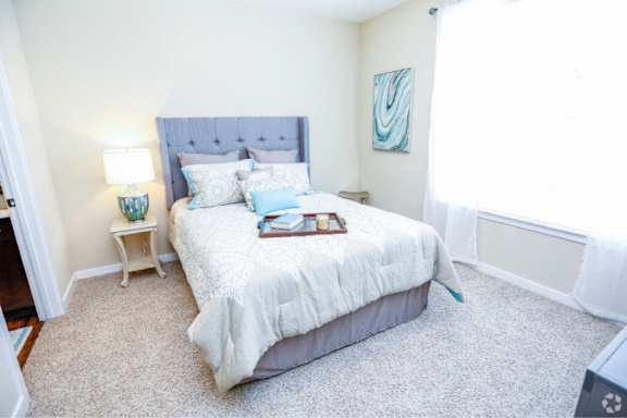 A bedroom with a large bed and a nightstand with a lamp.