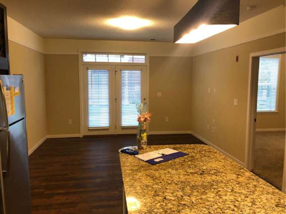 A kitchen with a granite countertop and a refrigerator on the left.