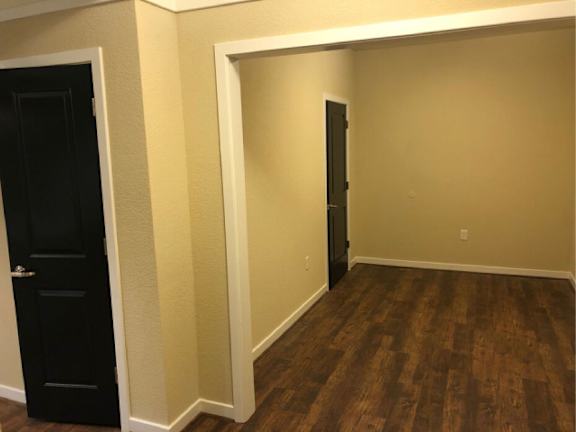 A room with a black door and wooden flooring.
