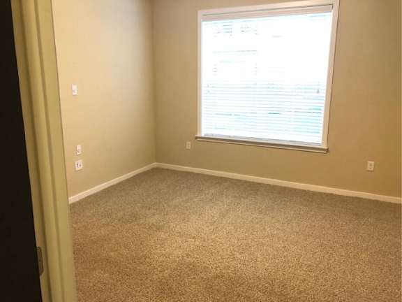 A room with a window and a carpeted floor.