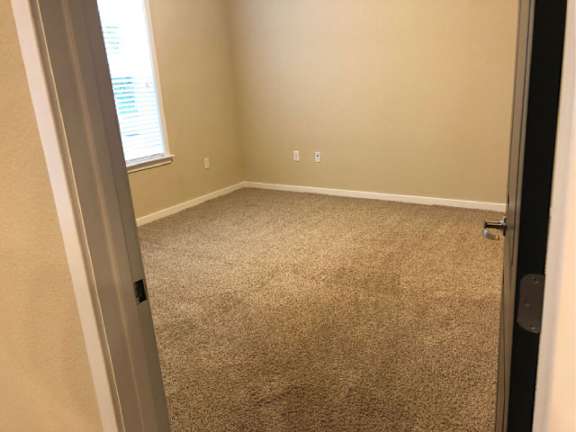 A room with a carpeted floor and a window.