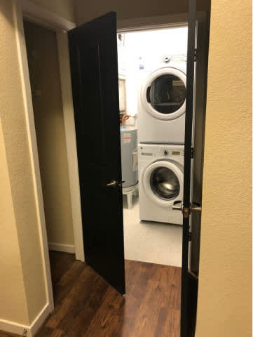 A black door is open to a small laundry room with a washer and dryer.