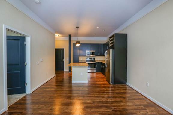 A kitchen with dark wood floors and a white island.