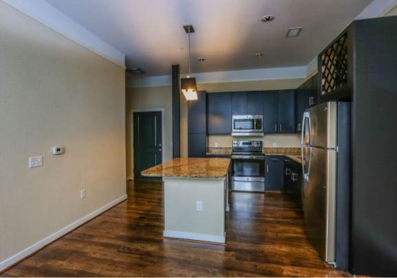 A kitchen with a granite countertop and stainless steel appliances.