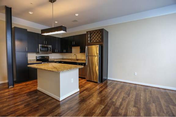 A kitchen with a black refrigerator and a white island.