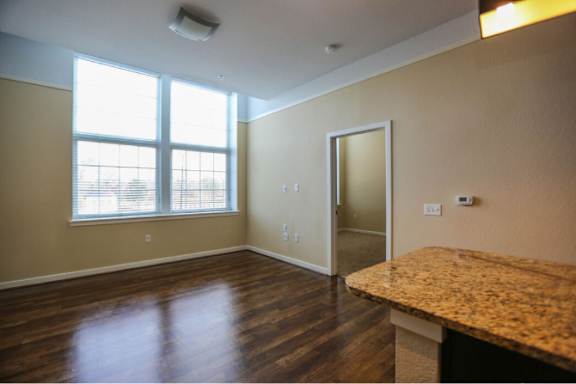 A room with a brown wooden floor and a large window.