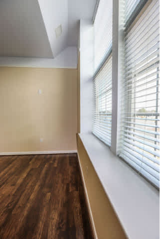 A room with a wooden floor and a window with blinds.