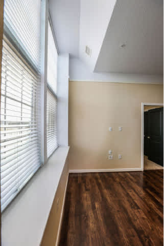 A room with a wooden floor and a window with blinds.