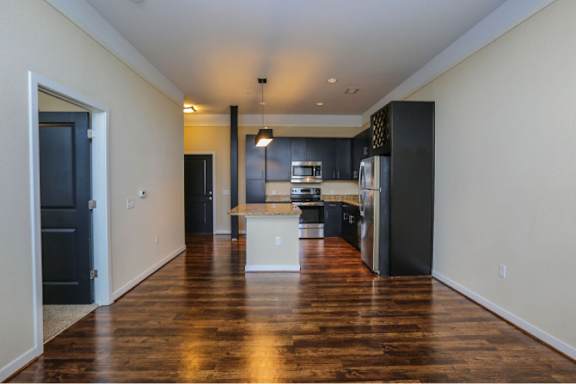 A kitchen with dark wood floors and a white island.