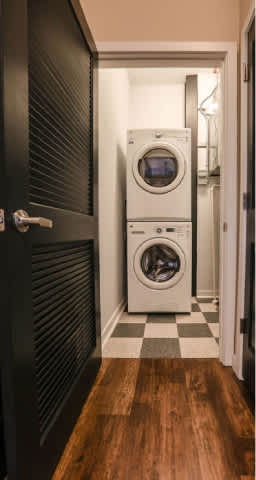 A white washing machine is in a small laundry room.