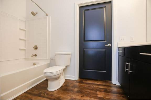 A white toilet sits in a bathroom next to a white bathtub.