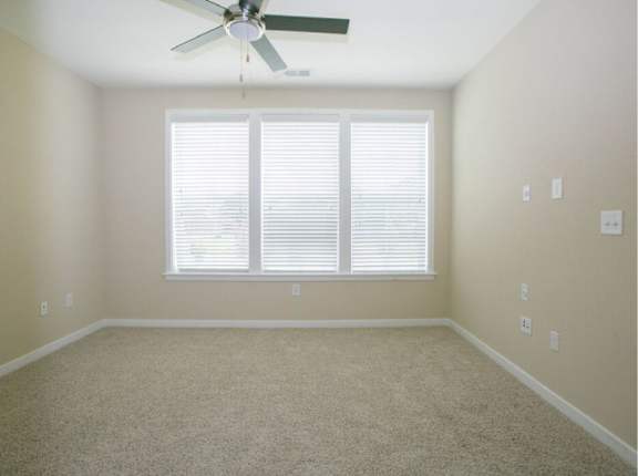 A room with a ceiling fan and a window with blinds.