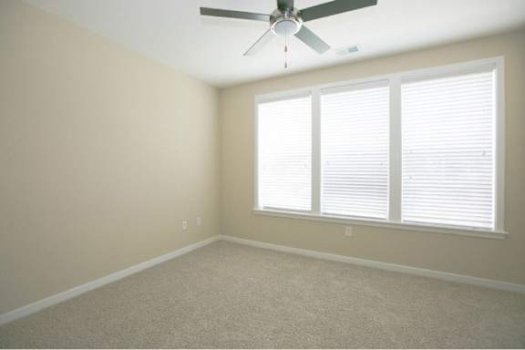 A room with a ceiling fan and a window with blinds.
