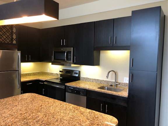 A kitchen with black cabinets and granite countertops.