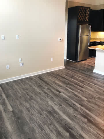 A kitchen with a black refrigerator and wooden flooring.