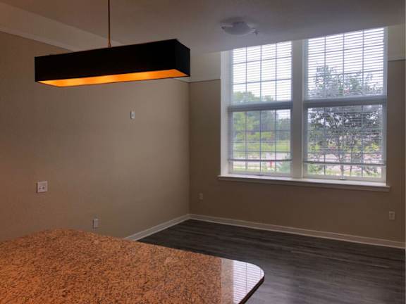 A room with a large window and a hanging light fixture.