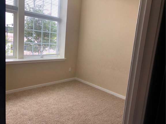A room with a window and carpeted floor.