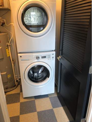 A white front load washing machine in a laundry room.